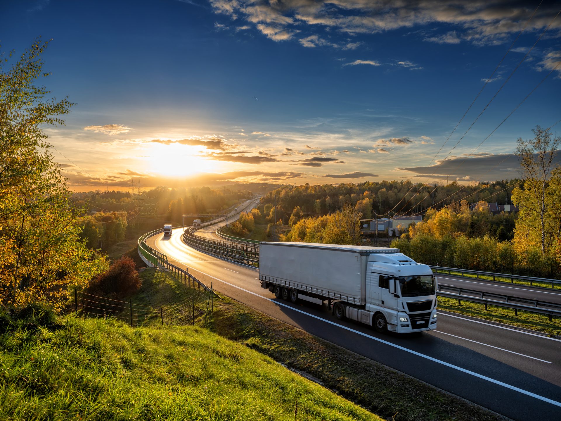 Trio de camions Dubourg au crépuscule devant le dépôt Canéjan en forêt de pins